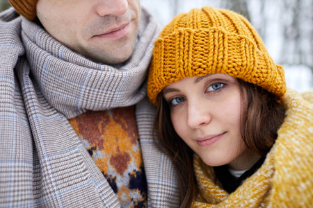 Close up of young woman resting head on partners shoulder and smiling while enjoying winter getaway...