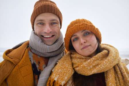 POV selfie photo of carefree young couple smiling at camera outdoors in winter, wearing warm clothesの写真素材