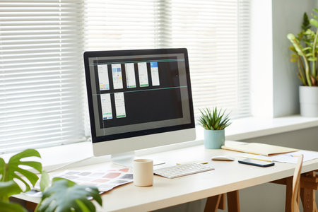Minimal background image of computer with mobile app designs on screen at workplace tableの写真素材