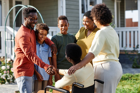 Portrait of big African American family with person in wheelchair chatting outdoors during gathering...