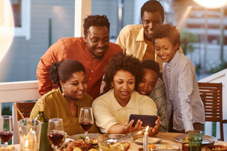 Portrait of African American family taking selfie photo at dinner in eveningの写真素材