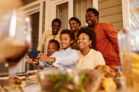 Portrait of happy African American family taking selfie photo at house terrace in eveningの写真素材