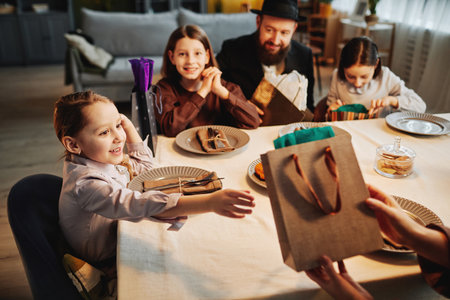 Portrait of excited little girl reaching for present at jewish family celebrationの写真素材
