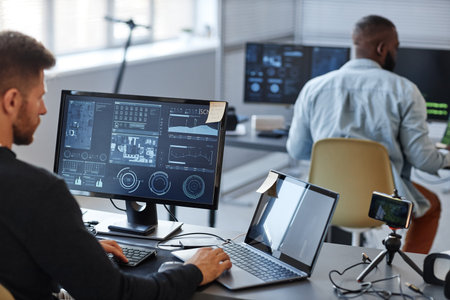 Portrait of male programmer or data specialist using computer in office with charts on screen, copy...