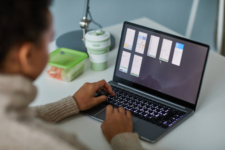 Close-up of young businesswoman typing on laptop and working with online project at table at office