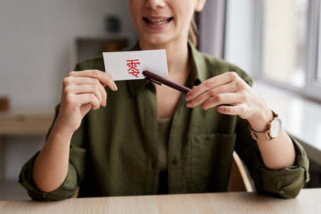 Hands of young confident tutor of Chinese language pointing at hieroglyph written with red highlighter on paper cardの写真素材