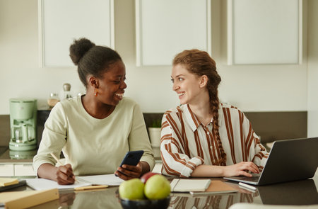 Portrait of two young women looking at each other and smiling while working on small business ideas...