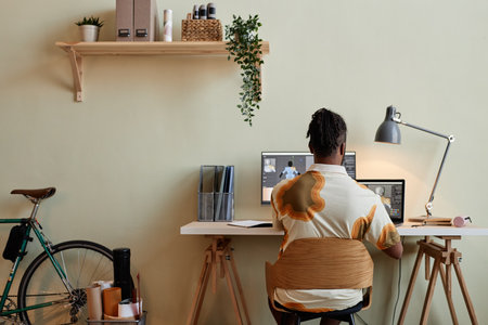 Back view at creative black man building digital 3D models at minimal home officeの写真素材