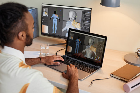 Back view at creative black man building digital 3D models and using multiple computer screens, copy spaceの写真素材
