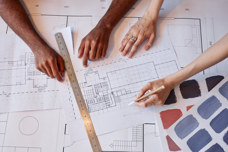 Top view of two architects working on floor plans for interior design project