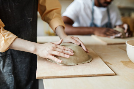 Close up of young woman shaping handmade ceramic bowl in cozy pottery studio, copy spaceの写真素材