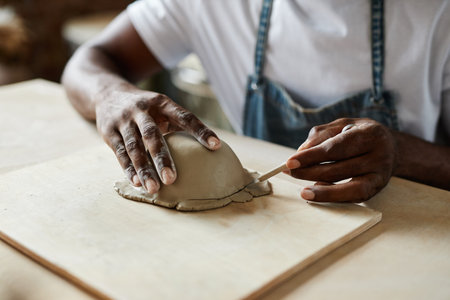 Close up of creative black man shaping ceramic bowl in cozy pottery studio, copy spaceの写真素材