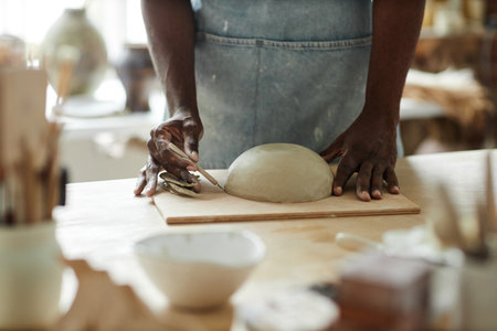 Warm toned closeup of man creating beautiful handmade bowl in pottery studioの写真素材