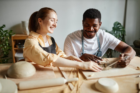 Portrait of carefree young couple enjoying pottery workshop together and making handmade ceramicsの写真素材