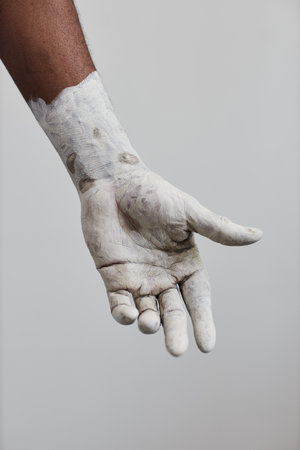 Vertical closeup of male hand covered in white paint, minimalの写真素材