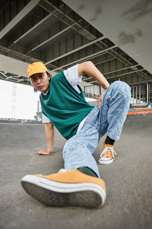 Fisheye of young Asian man dancing hip hop outdoors and wearing colorful street style clothes in...