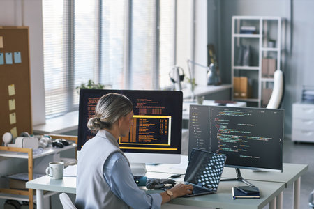 Female sceintist with bionic arm working on computer in office of modern company