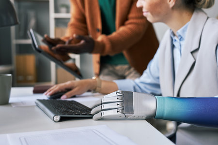 Businesswoman with prosthetic arm discussing docuemnt with tablet screen with colleagueの写真素材