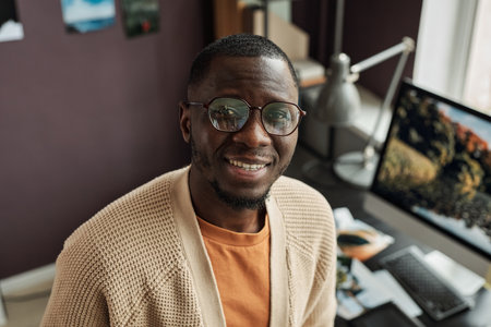 Happy Black designer in glasses standing in office of designe studio and looking at camera