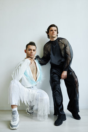 Full length shot of two non binary young people wearing extravagant fashion outfits against whiteの写真素材