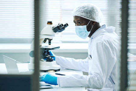 Graphic side view portrait of black male scientist working in laboratory with microscope