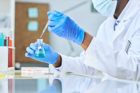 Close up of lab technician taking liquid samples with pipette while doing medical research