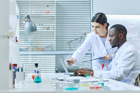 Side view portrait of two scientists using laptop in medical laboratory while doing research, copy spaceの写真素材