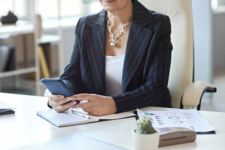 Close up of female boss using smartphone at workplace in office, copy space