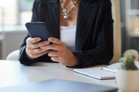 Closeup of female manager using smartphone at workplace in office, copy spaceの写真素材