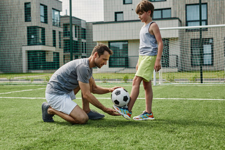 Side view portrait of young father teaching son football in outdoor court, copy spaceの写真素材