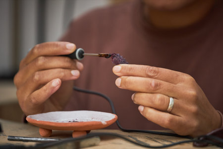 Close up of female jeweler shaping wax mold while creating handmade jewelryの写真素材