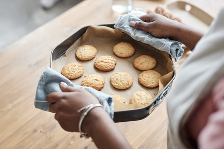 Closeup of little girl holding tray with homemade cookies while enjoying baking in kitchen , copy...