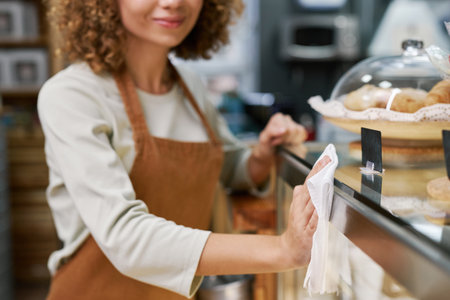 Closeup image of coffeeshop barista cleaning surfaces before opening in the morningの写真素材