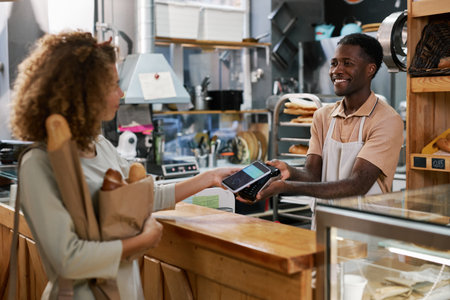 Customer using mobile payment service when buying bread in local bakery