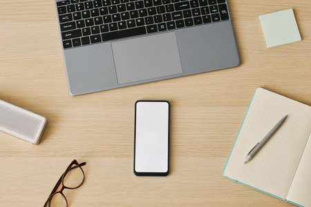 Minimal top view of smartphone with white screen mockup at desk workplace, copy space