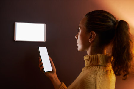 Side view portrait of young woman using digital smart home system with screen mockups