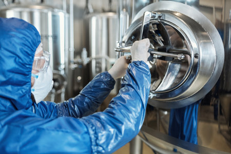 Worker wearing protective suit opening vault lock in factory workshop