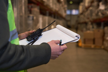 Close up of unrecognizable worker holding clipboard in warehouse with blank white mock up, copy spaceの写真素材