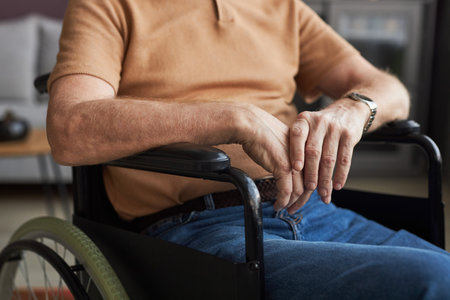 Close-up of senior man with disability sitting on wheelchair in the roomの写真素材