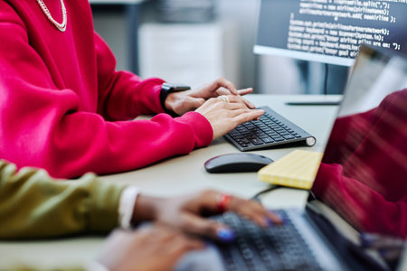 Close up of young person typing at computer keyboard while writing code in software development office, magenta accentの写真素材