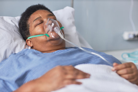 Black senior woman sleeping on bed in hospital room with oxygen support mask