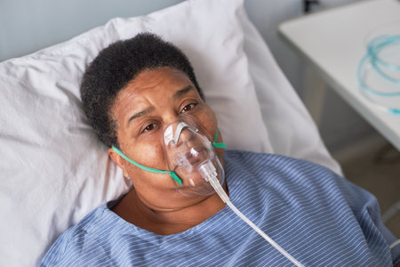 Portrait of African American senior woman in hospital room looking at camera, oxygen supportの写真素材