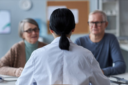 Back view of female doctor working with senior couple in medical clinic, copy spaceの写真素材