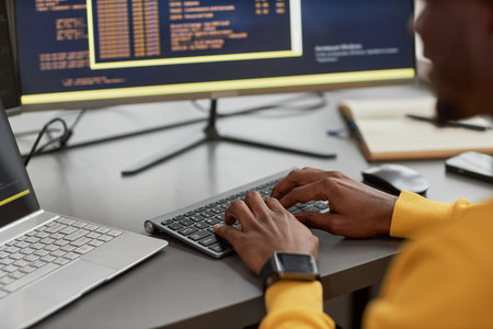 Close up of unrecognizable black man typing at keyboard while writing code in IT development...