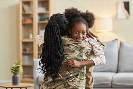 Little girl smiling at camera while embracing her mother during her returning to homeの写真素材