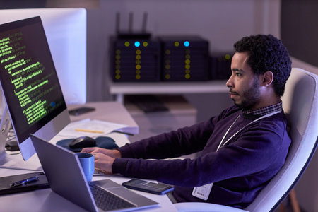 Side view portrait of bearded man using computers and writing code in neon lightの写真素材