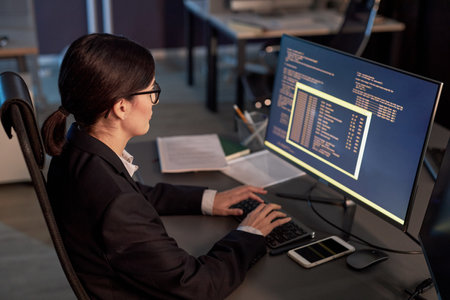 High angle portrait of female software developer writing code while using computer at workplace in officeの写真素材