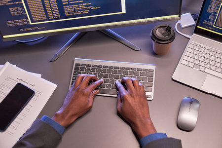Top view of male hands typing at computer keyboard at workplace in high tech IT office