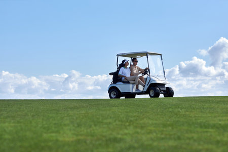 Minimal background image of sporty couple driving golf cart across field with center line horizon, copy spaceの写真素材