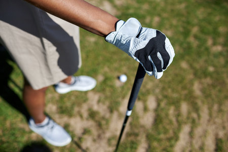 Top view closeup of gloved female hand holding golf club outdoors against grass, copy spaceの写真素材